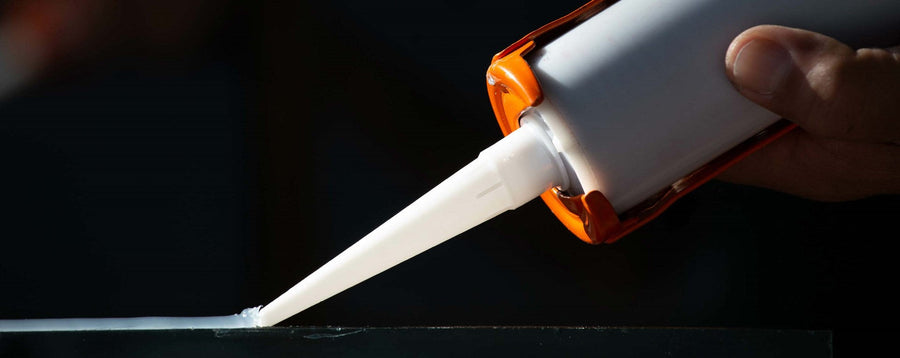 Sealant cartridge and nozzle against a dark background