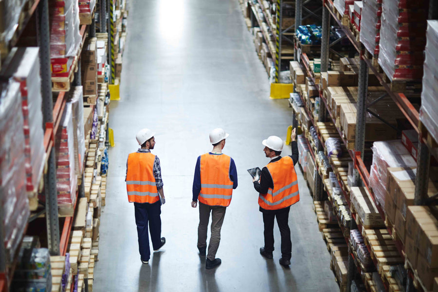 Warehouse racking and workers reviewing stored industrial supplies